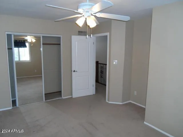 an empty room with closet and a chandelier fan