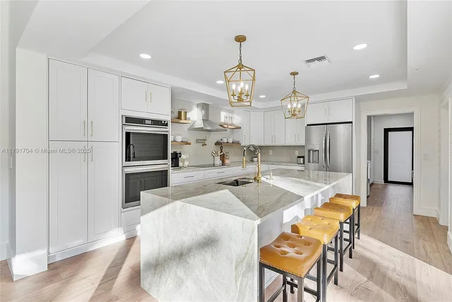 a large kitchen with kitchen island a large counter space stainless steel appliances and cabinets