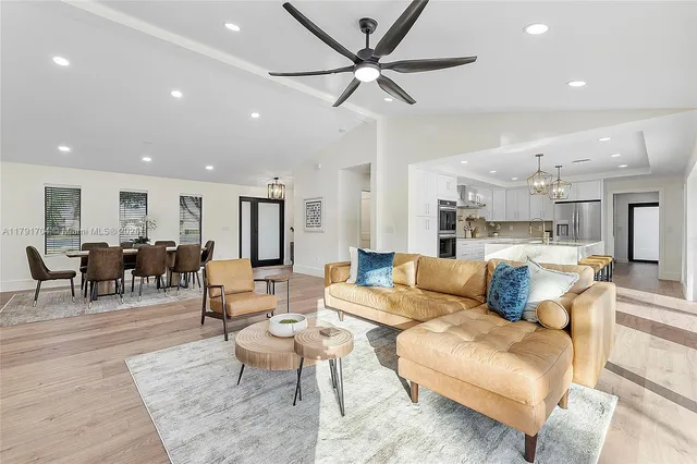 a living room with furniture kitchen view and a chandelier