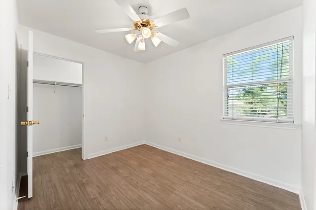 an empty room with a window and a ceiling fan