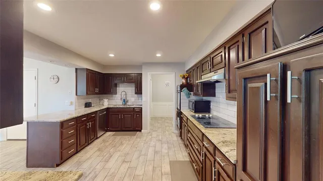 a kitchen with stainless steel appliances granite countertop lots of counter top space and wooden floor
