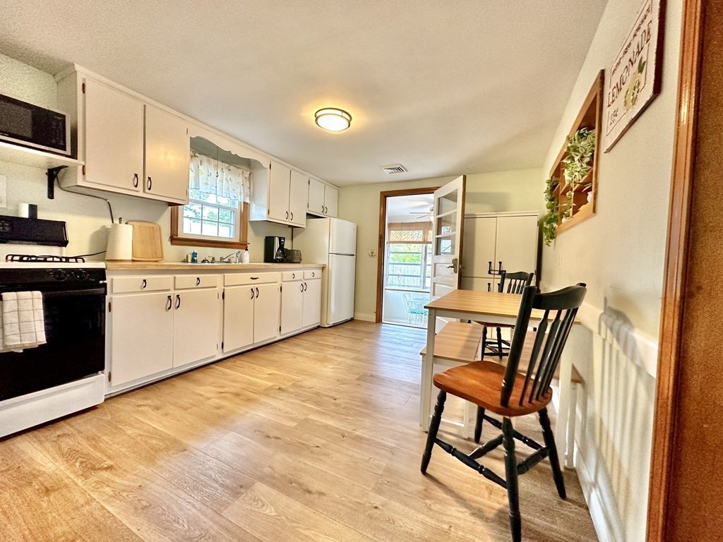 101 Swan River Road Dennis, MA 02670 - Photo 12 of 19 a kitchen with white cabinets and wooden floor