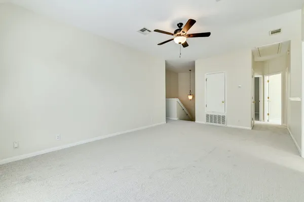 an empty room with ceiling fan and windows