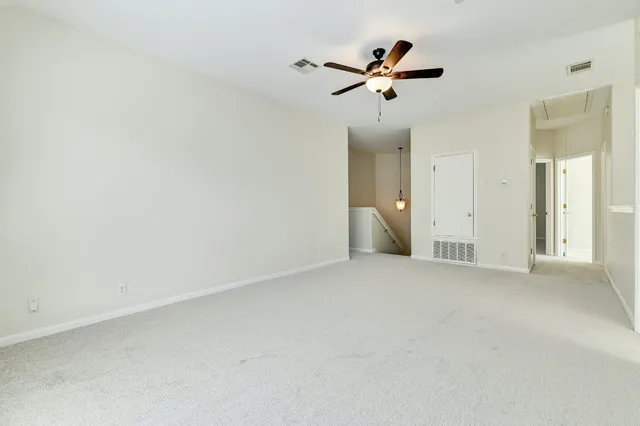 an empty room with ceiling fan and windows