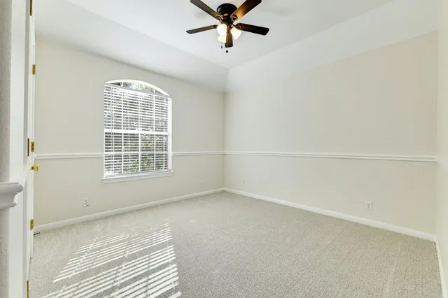 an empty room with a chandelier fan and windows