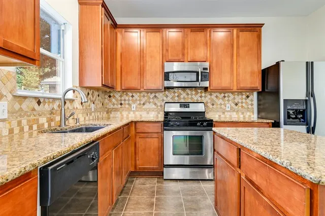 a kitchen with stainless steel appliances granite countertop a sink a stove and a microwave