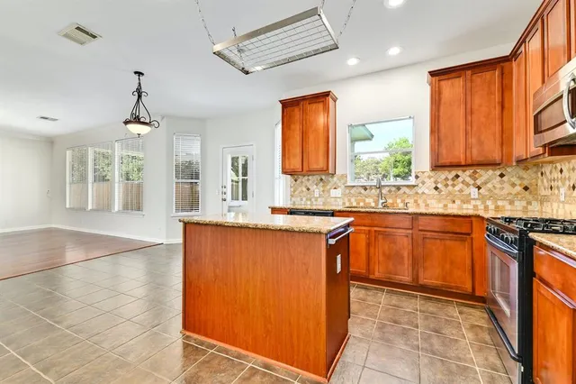 a large kitchen with stainless steel appliances granite countertop a stove a sink a window and dining table