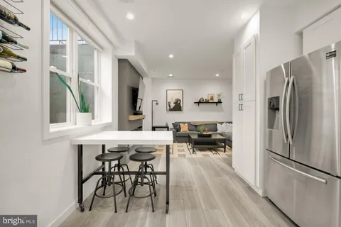 a kitchen with stainless steel appliances a refrigerator a stove a dining table and chairs with wooden floor