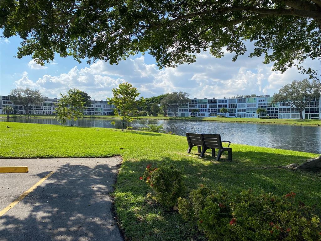 4047 Cambridge C, Unit 4047 Deerfield Beach, FL 33442 - Photo 23 of 43 a view of a lake with a garden and a bench
