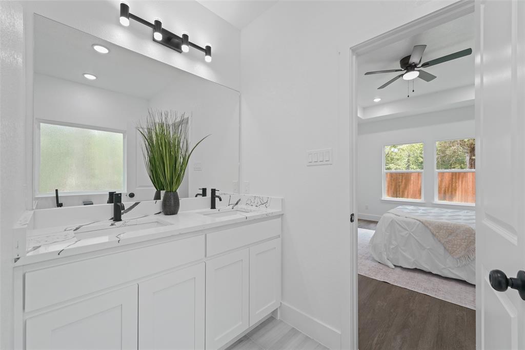 122 East Beachwood Loop Trinidad, TX 75163 - Photo 24 of 35 Bathroom vanity featuring a dual sink with matte black fixtures, a single large mirror, white cabinetry, and a window with frosted glass