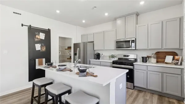 a kitchen with a sink stove and white cabinets with wooden floor