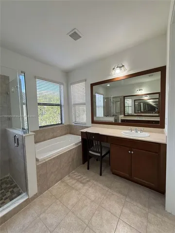 a spacious bathroom with a tub sink and mirror