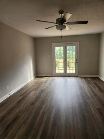 a view of an empty room with a window and wooden floor