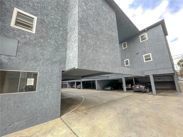 a view of a house with a barbeque and large trees