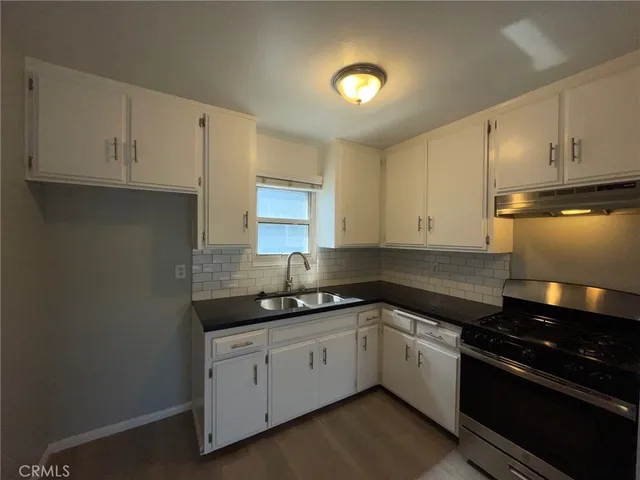 a white kitchen with sink and cabinets