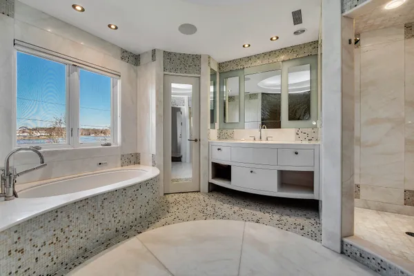 a bathroom with a tub sink shower and mirror