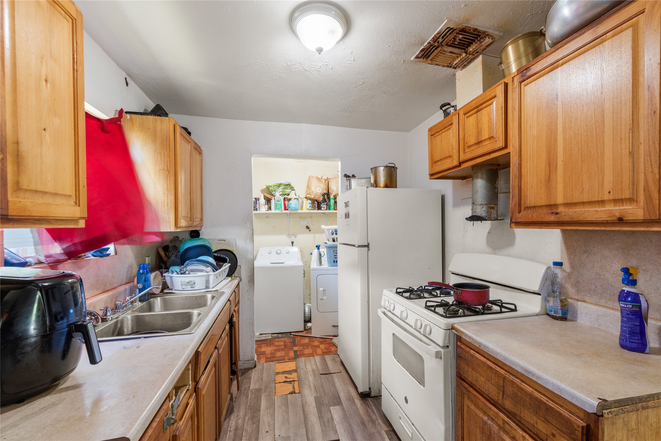 7105 Bethune Avenue Austin, TX 78752 - Photo 4 of 13 Kitchen featuring white appliances, washer and clothes dryer, light wood-style floors, and light countertops