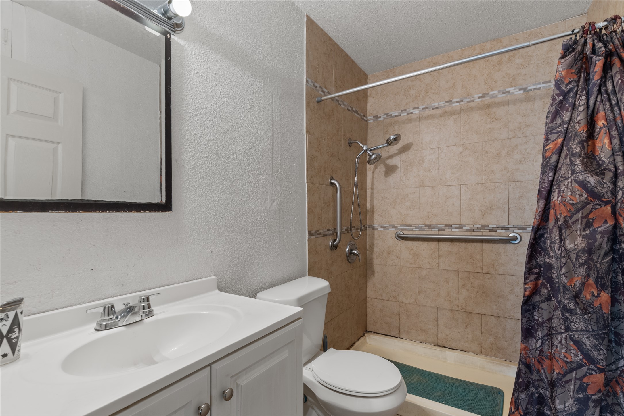 7105 Bethune Avenue Austin, TX 78752 - Photo 5 of 13 Bathroom featuring vanity, a tile shower, a textured wall, and a textured ceiling