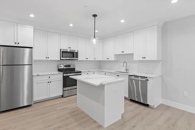 a kitchen with cabinets stainless steel appliances and wooden floor