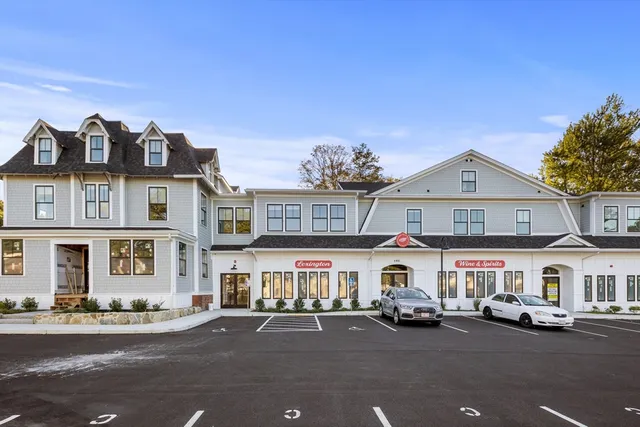 a front view of a building with lot of cars and trees