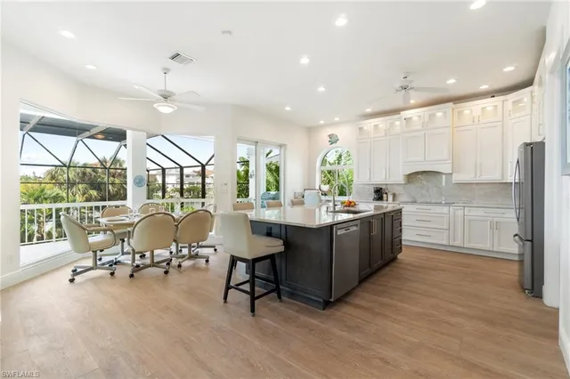 a kitchen with stainless steel appliances kitchen island granite countertop a table chairs and a refrigerator