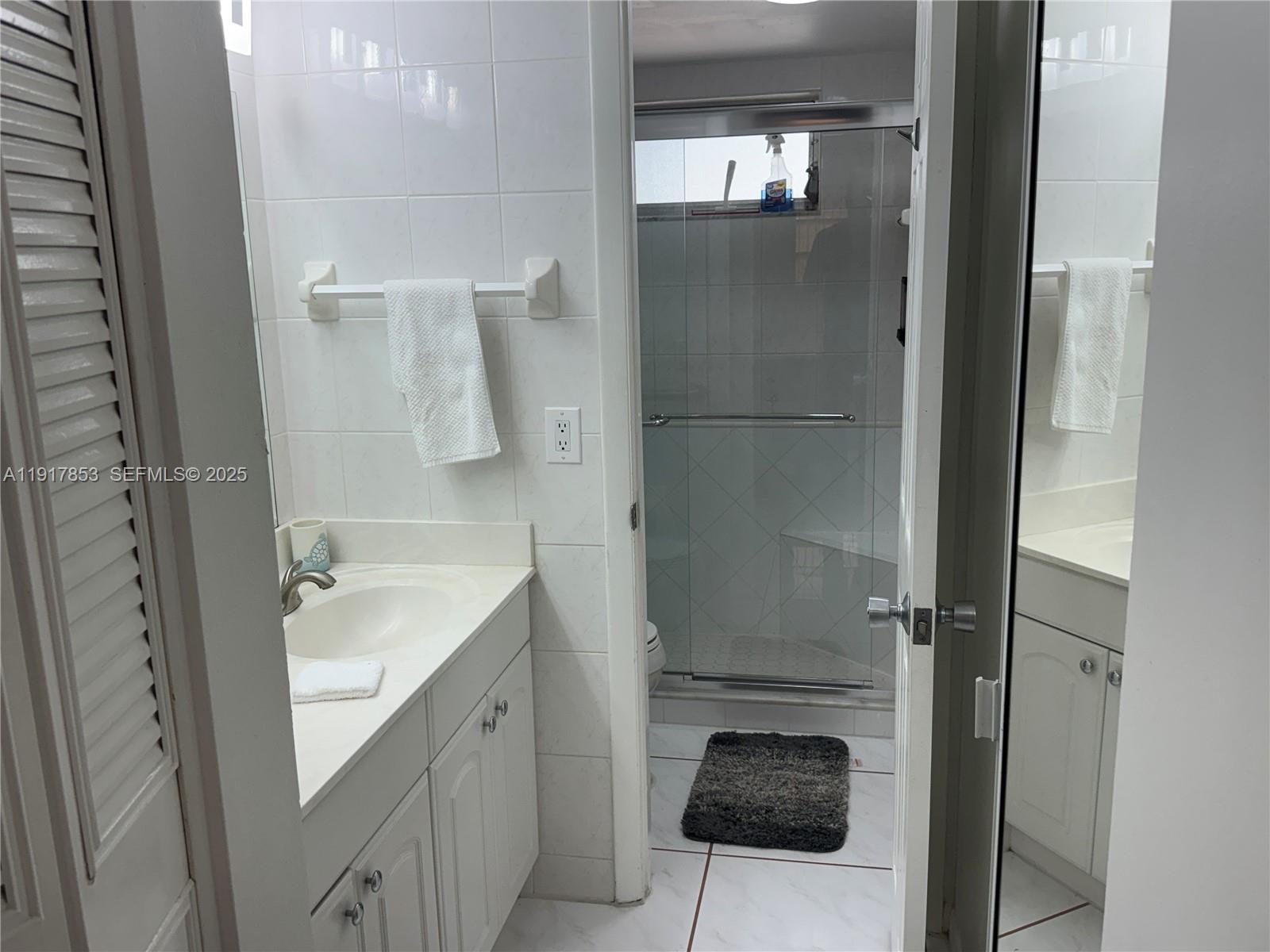 6050 Northwest 64th Avenue, Unit 306 Tamarac, FL 33319 - Photo 17 of 31 a bathroom with a granite countertop sink a toilet and shower