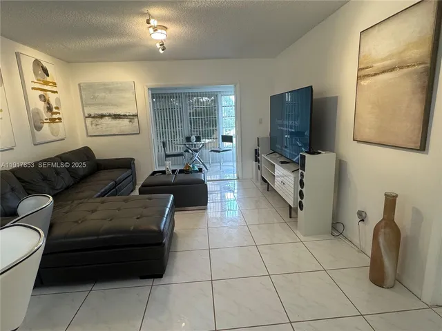 a living room with furniture a flat screen tv and a window
