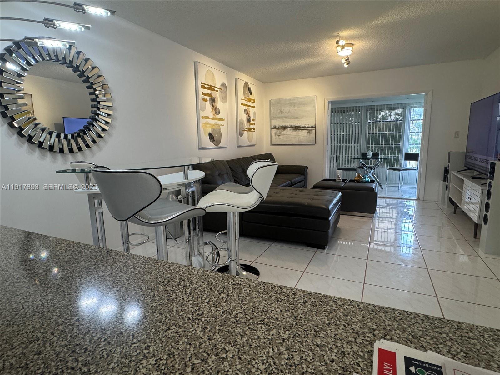 6050 Northwest 64th Avenue, Unit 306 Tamarac, FL 33319 - Photo 9 of 31 a living room with furniture and a chandelier