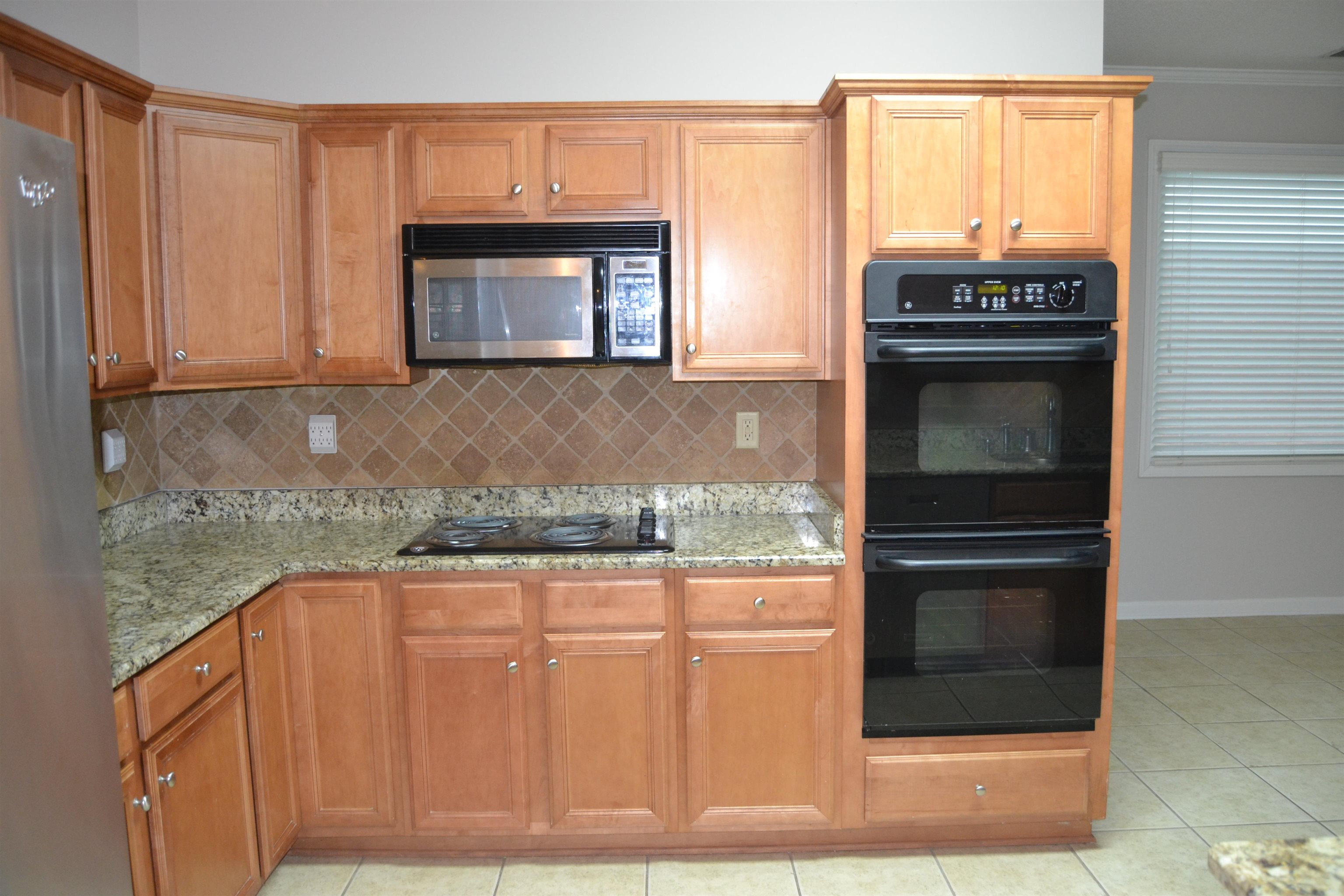 10486 Juneau Way Collierville, TN 38017 - Photo 18 of 33 Kitchen featuring tasteful backsplash, light stone counters, crown molding, black appliances, and light tile patterned flooring