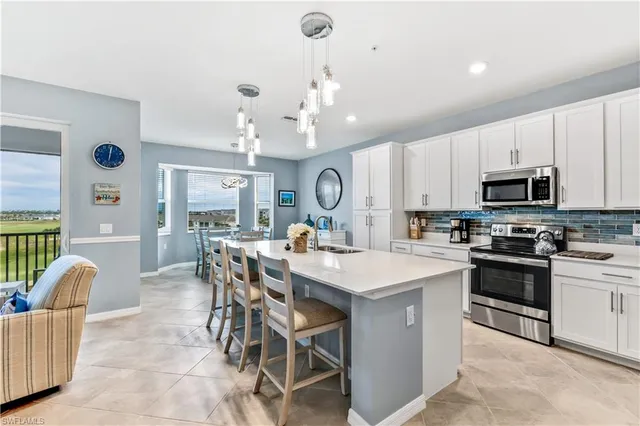 a large kitchen with kitchen island granite countertop a sink a stove a dining table and chairs