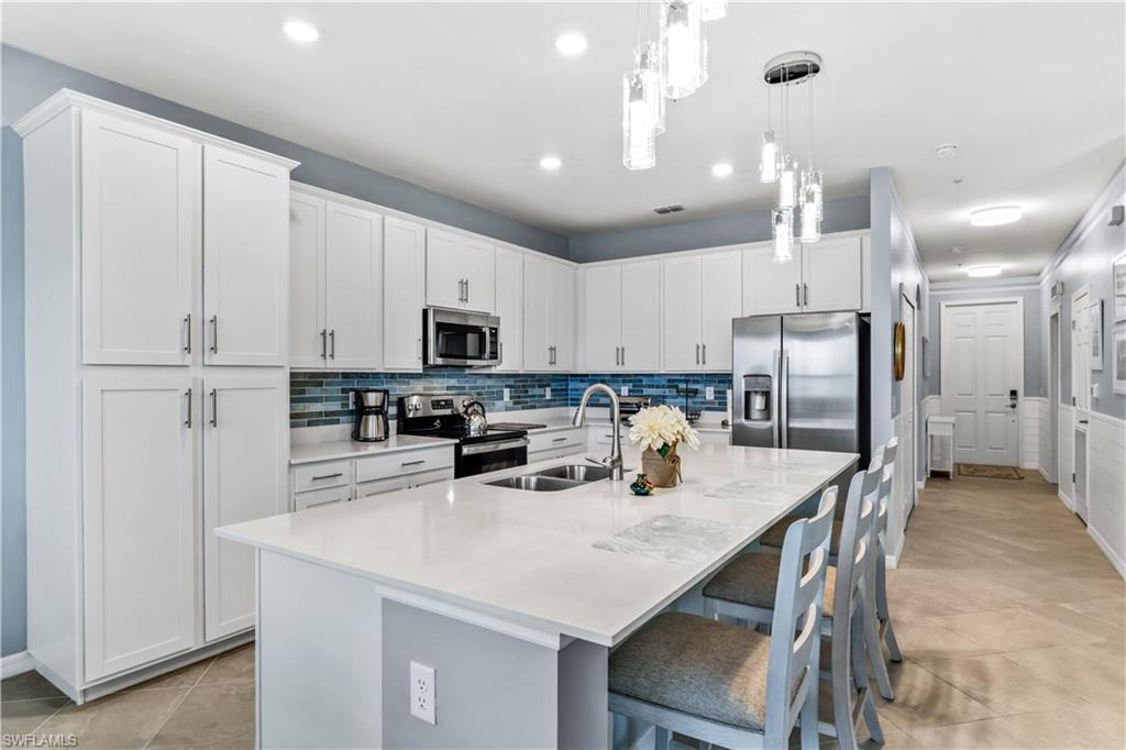 43989 Boardwalk Loop, Unit 2042 Babcock Ranch, FL 33982 - Photo 5 of 12 a kitchen with stainless steel appliances a refrigerator a stove a sink a dining table and chairs