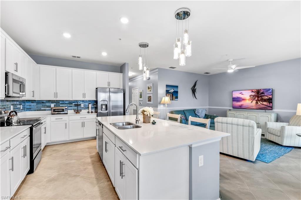 43989 Boardwalk Loop, Unit 2042 Babcock Ranch, FL 33982 - Photo 6 of 12 a open kitchen with stainless steel appliances kitchen island granite countertop a sink dishwasher and white cabinets with wooden floor