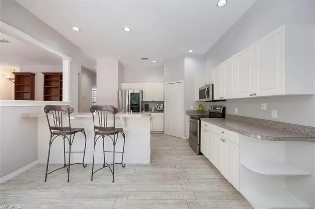 a large kitchen with cabinets chairs and a dining table