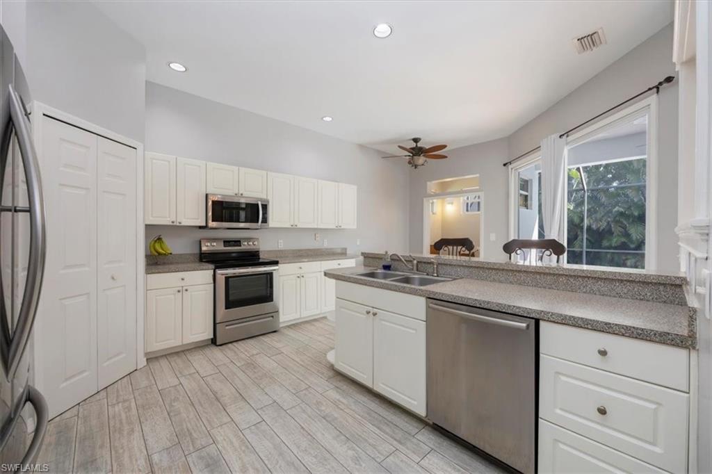 496 Raven Way Naples, FL 34110 - Photo 9 of 31 a kitchen with granite countertop white cabinets and white appliances