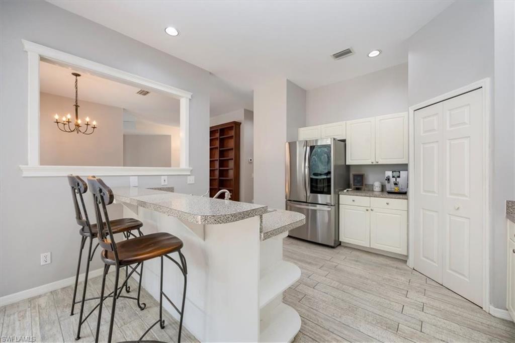 496 Raven Way Naples, FL 34110 - Photo 10 of 31 a kitchen with a dining table chairs refrigerator and cabinets