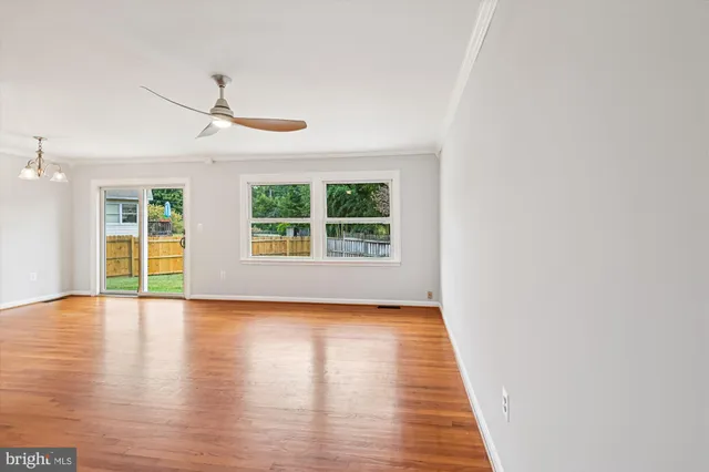 an empty room with wooden floor chandelier and windows