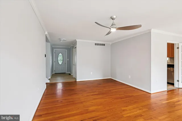 an empty room with wooden floor and ceiling fan