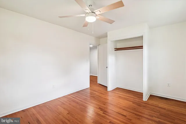an empty room with wooden floor and a ceiling fan