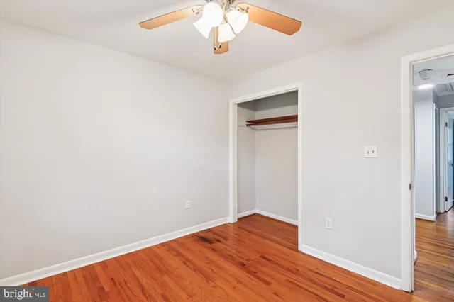 an empty room with wooden floor closet and windows