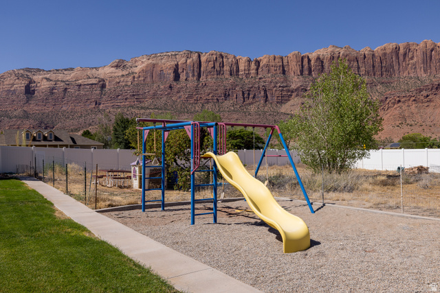 4635 East Sunny Acres Lane Moab, UT 84532 - Photo 25 of 56 Outdoor play structure with a yellow slide and swings, set on a gravel base