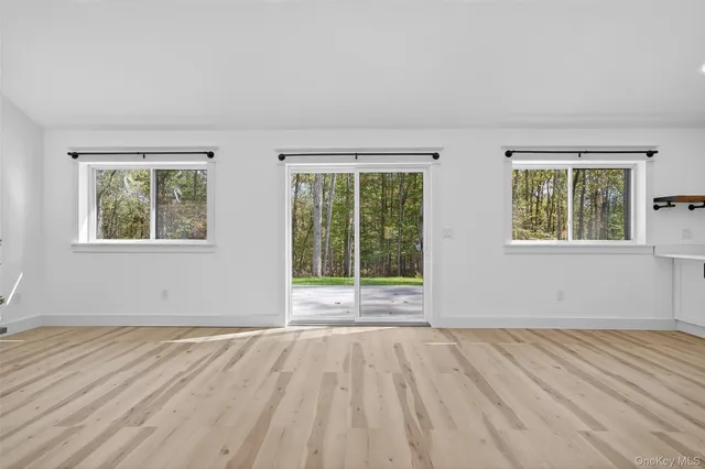 a view of empty room with wooden floor and window