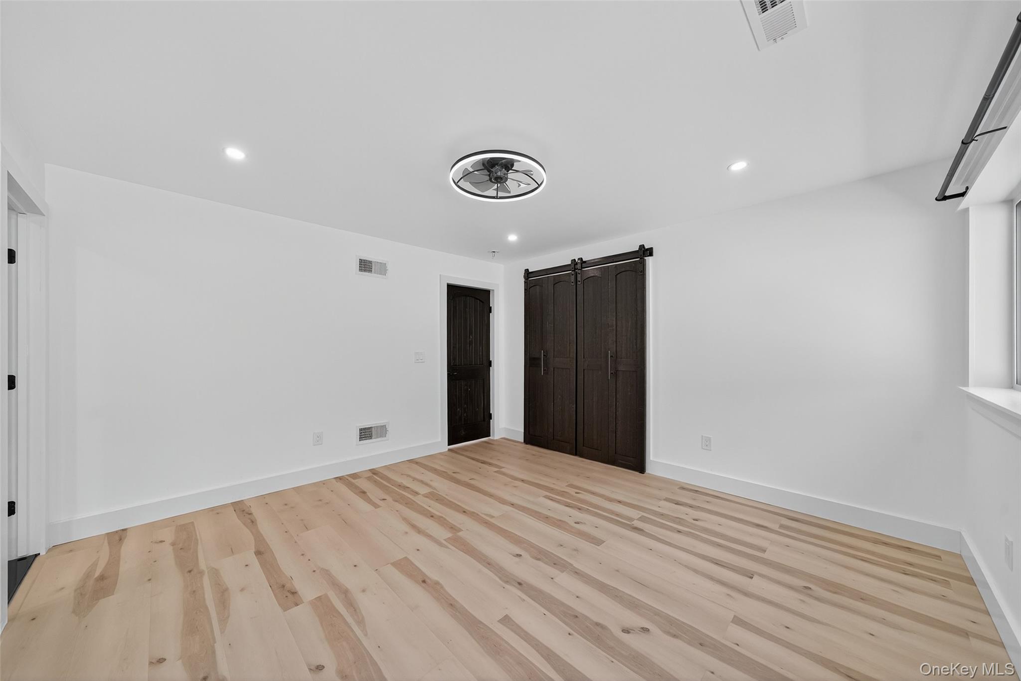 273 Perry Pond Road Narrowsburg, NY 12764 - Photo 27 of 49 Unfurnished bedroom featuring a barn door, recessed lighting, light wood-type flooring, and a closet