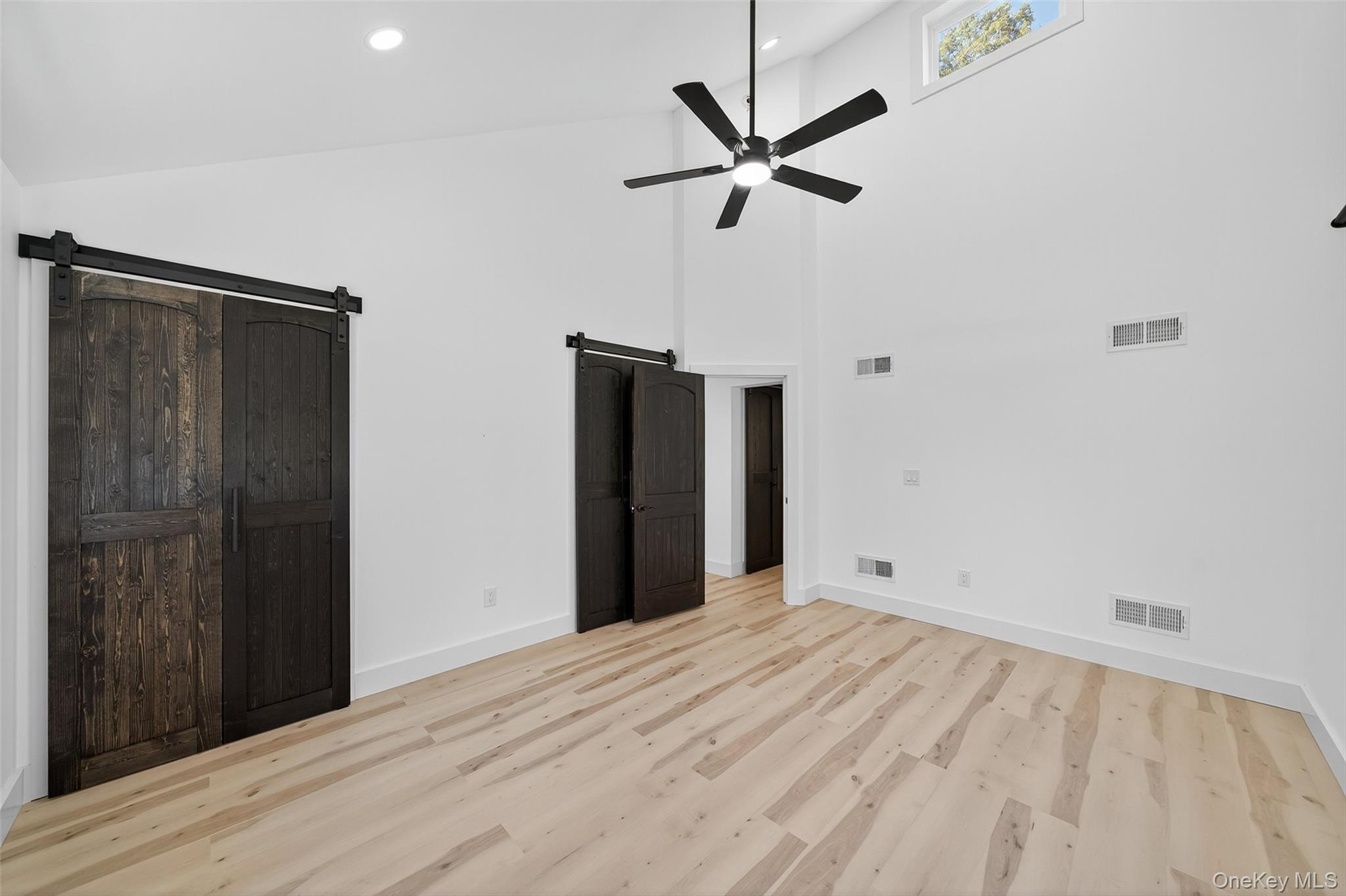 273 Perry Pond Road Narrowsburg, NY 12764 - Photo 33 of 49 Unfurnished bedroom featuring high vaulted ceiling, a barn door, light wood finished floors, a ceiling fan, and recessed lighting
