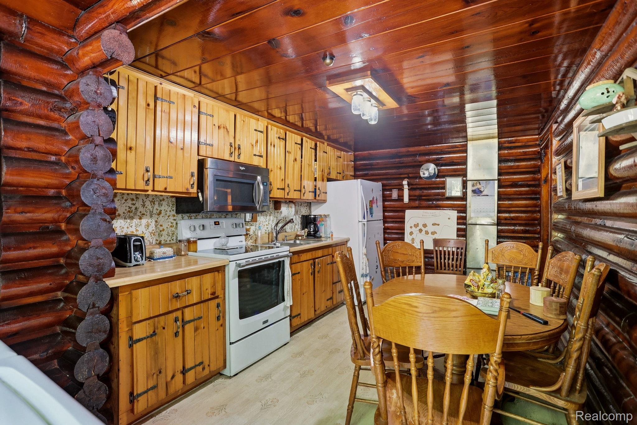 3814 South Towerline Road Bridgeport, MI 48722 - Photo 19 of 52 Log cabin kitchen and dining area featuring natural wood walls, wood-finish flooring, and a full suite of appliances