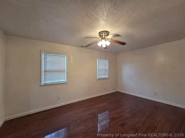 a view of an empty room with a chandelier fan and a window