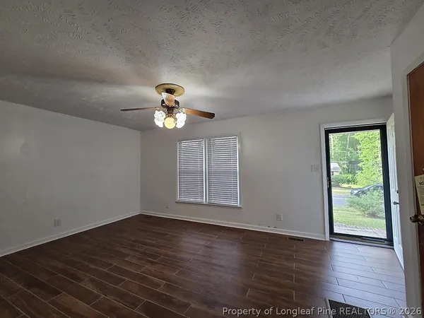 a view of an empty room with wooden floor and a window