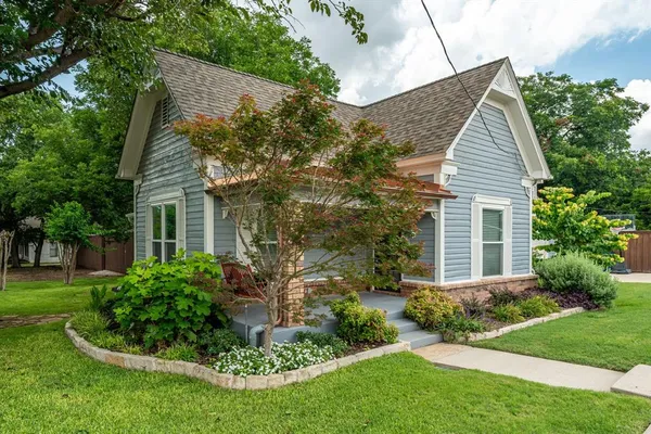 a view of house with a yard and potted plants