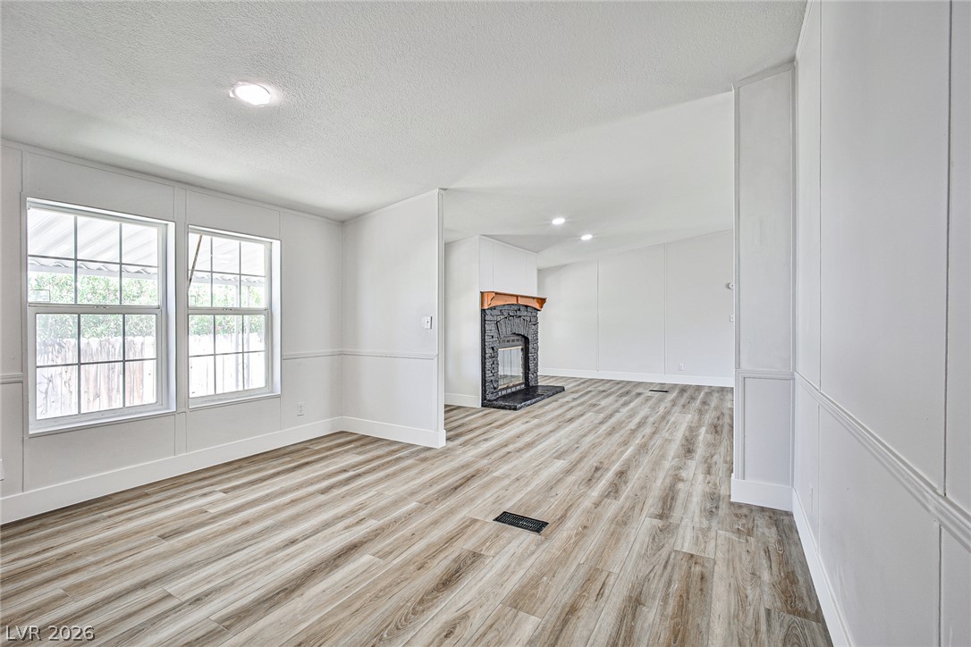 273 Aztec Lane Henderson, NV 89015 - Photo 13 of 28 A well-lit living area features warm wood-look flooring and a cozy corner fireplace.
