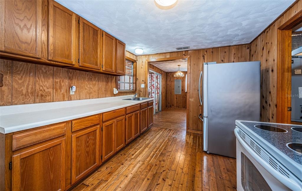 6423 Bass Road Weeki Wachee, FL 34607 - Photo 15 of 49 a kitchen with stainless steel appliances granite countertop a refrigerator a sink dishwasher and wooden cabinets with wooden floor