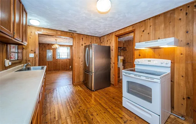 a kitchen with stainless steel appliances granite countertop a refrigerator a stove and a wooden floors